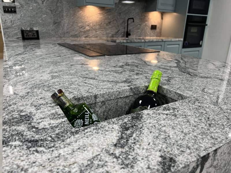 A bottle of wine is sitting in the middle of a granite countertop.